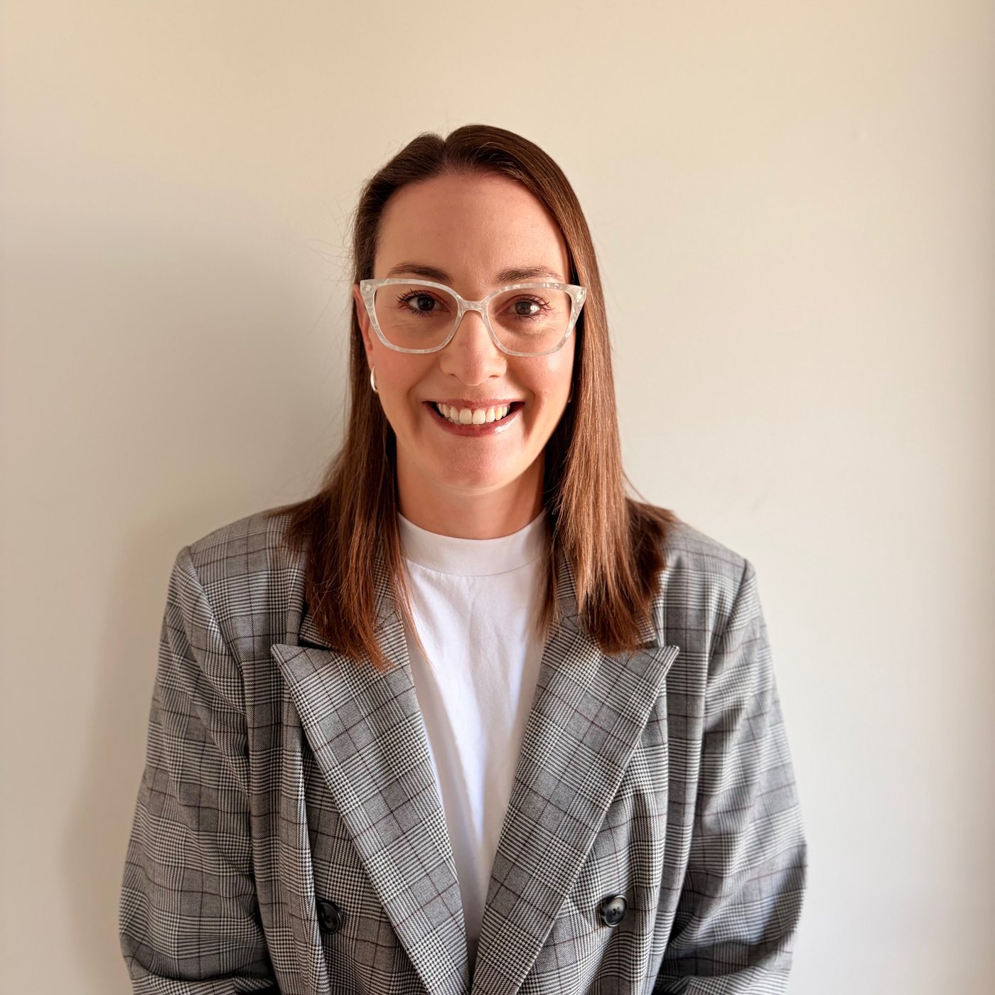 Author Hannah E. Marks smiling warmly, wearing glasses and a checked blazer.